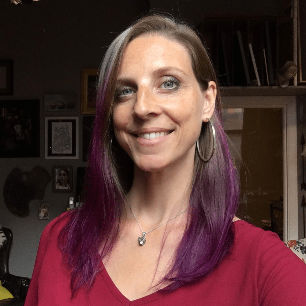 Julie Beck Workshop instructor smiling in studio headshot, purple-highlighted hair and hoop earrings, warm natural lighting.