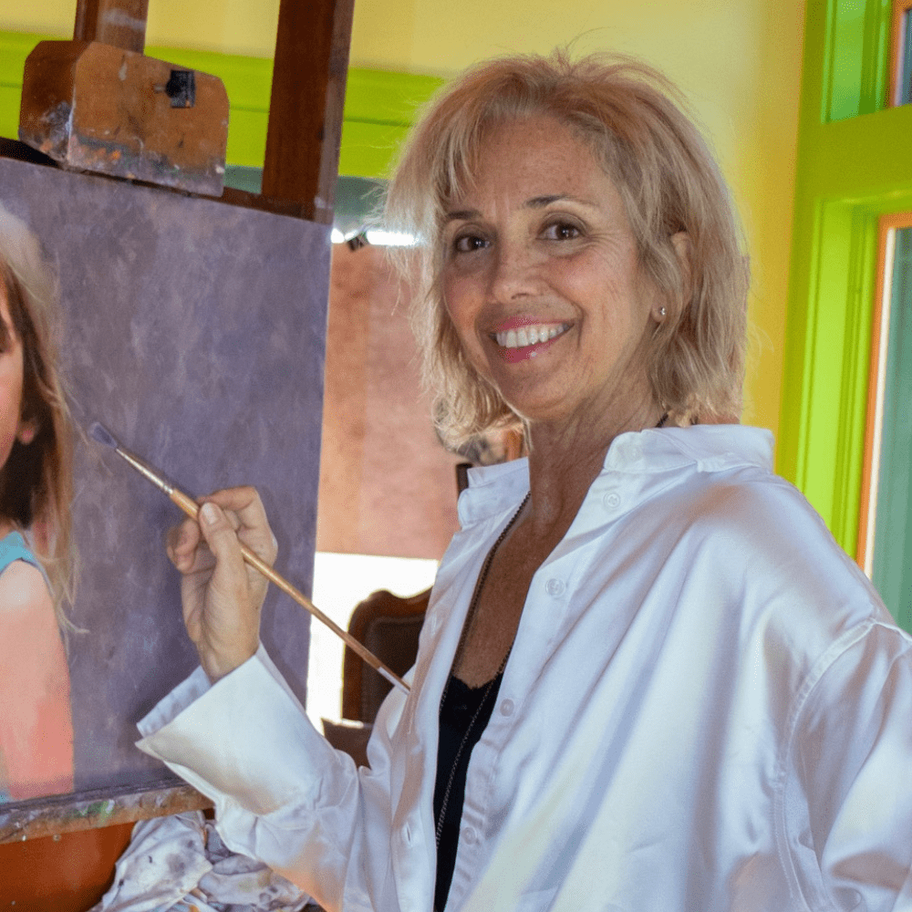 catherine-hafer-artist-at-easel Catherine Hafer painting at her easel, award winning portrait artist and instructor preparing panels for her Fall 2025 workshop.